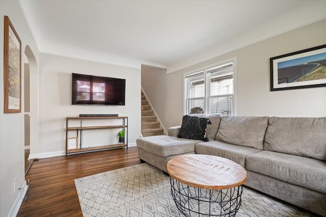 living area featuring stairway, arched walkways, baseboards, and wood finished floors