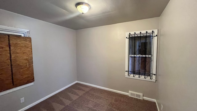 carpeted empty room featuring baseboards and visible vents
