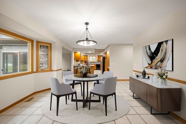 dining space featuring baseboards, a notable chandelier, and light tile patterned floors
