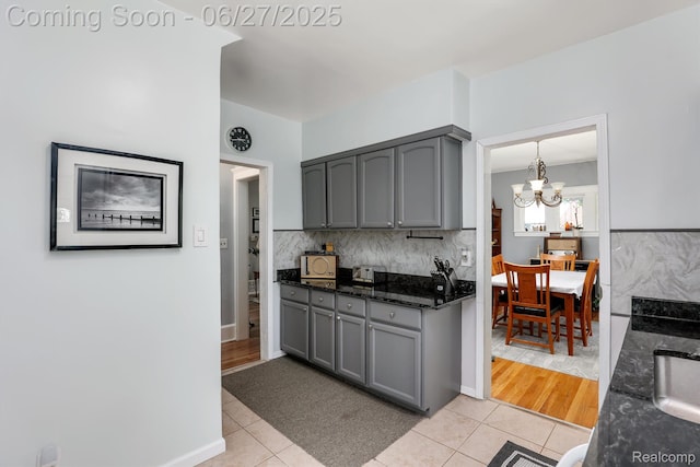 879 Lawrence St, Detroit, MI 48202 - kitchen with gray cabinetry, light tile patterned flooring, dark stone countertops, and a chandelier