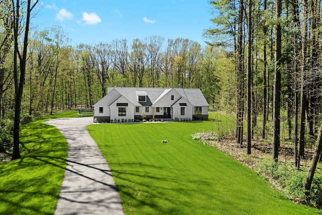 modern inspired farmhouse with a front lawn, driveway, and a forest view