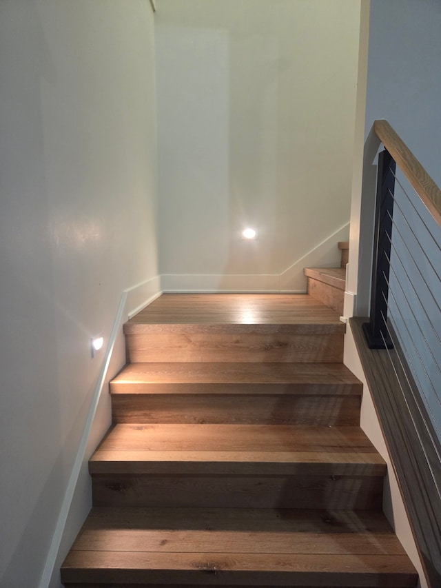 stairs featuring baseboards, wood finished floors, and a relaxing sauna