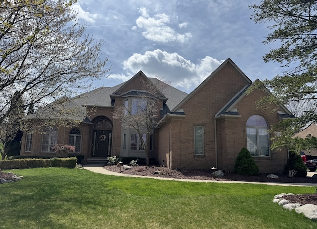 french country style house with a front yard and brick siding