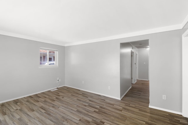 unfurnished room featuring baseboards, wood finished floors, and visible vents