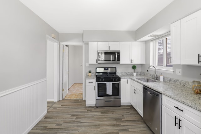 kitchen with a sink, wood finished floors, white cabinets, and stainless steel appliances