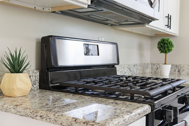 details with stainless steel range with gas stovetop, decorative backsplash, and white cabinets