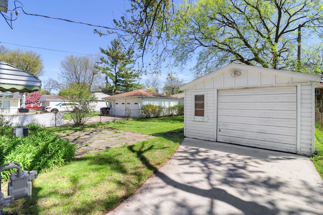 detached garage featuring concrete driveway and fence