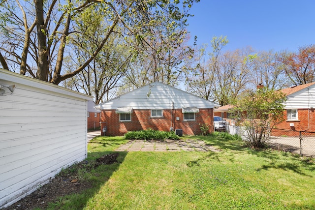 back of property featuring fence, a yard, and brick siding