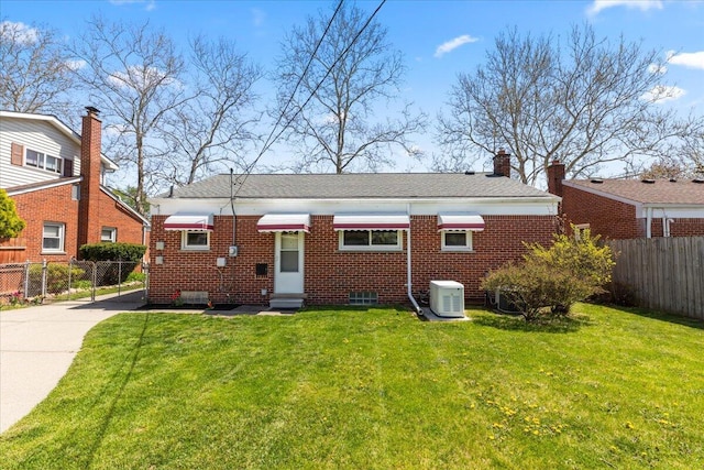 back of property with fence, central AC unit, a yard, and brick siding