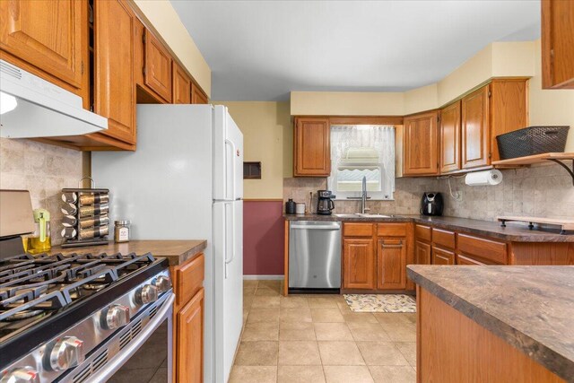 kitchen featuring a sink, appliances with stainless steel finishes, decorative backsplash, and dark countertops