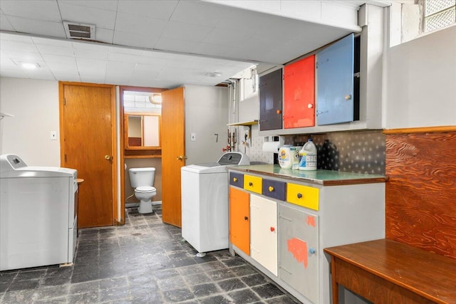 kitchen with dark floors, washing machine and dryer, and visible vents