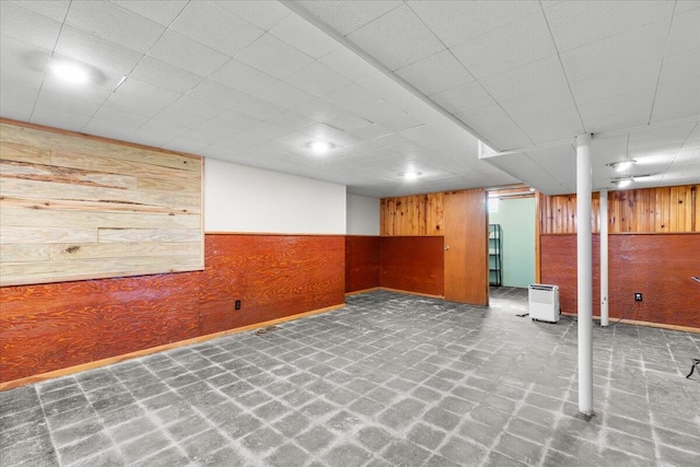 finished below grade area featuring baseboards, wood walls, and a wainscoted wall