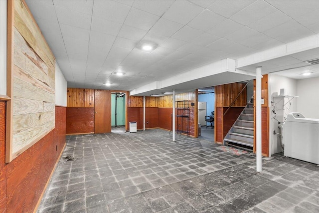 finished basement featuring washer / clothes dryer, wood walls, and stairs