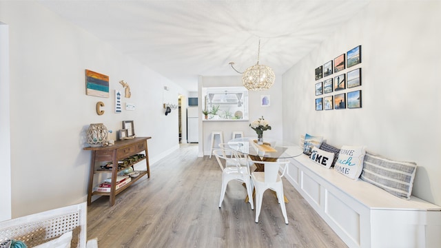 dining space featuring baseboards, light wood-style flooring, and a notable chandelier
