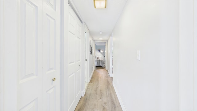 corridor featuring baseboards and light wood-style floors