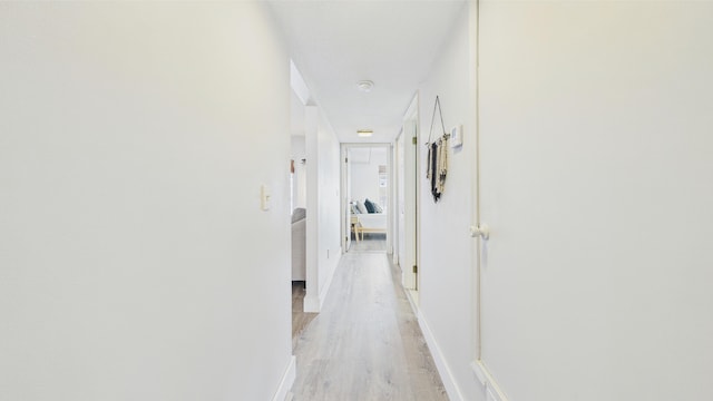 corridor featuring baseboards and light wood-style flooring