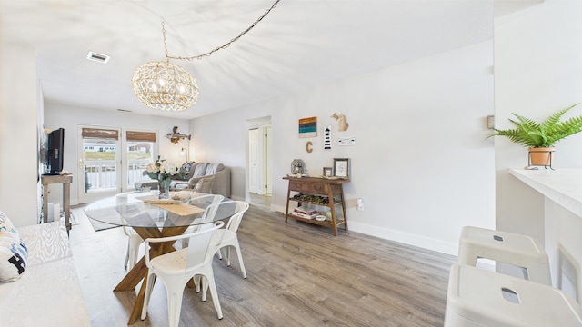 dining room with a chandelier, baseboards, visible vents, and light wood-type flooring