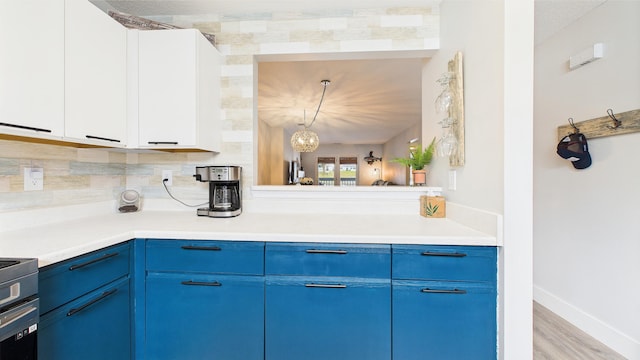 kitchen with backsplash, blue cabinets, wood finished floors, light countertops, and baseboards