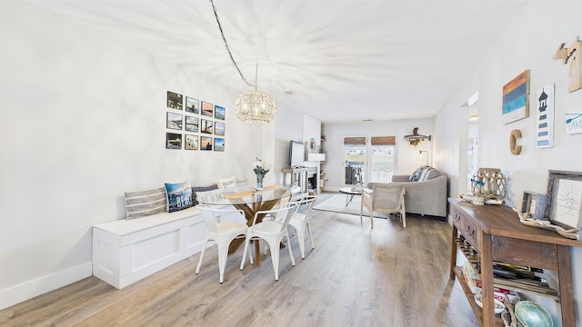 dining room featuring baseboards, light wood-style flooring, and a notable chandelier