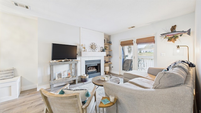 living area featuring visible vents, baseboards, wood finished floors, and a large fireplace