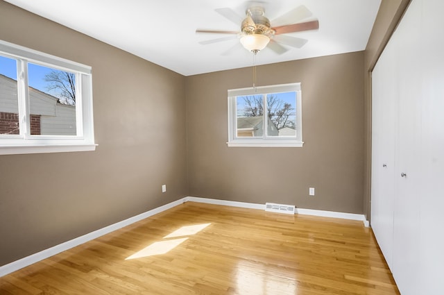 empty room featuring a healthy amount of sunlight, baseboards, light wood-type flooring, and visible vents
