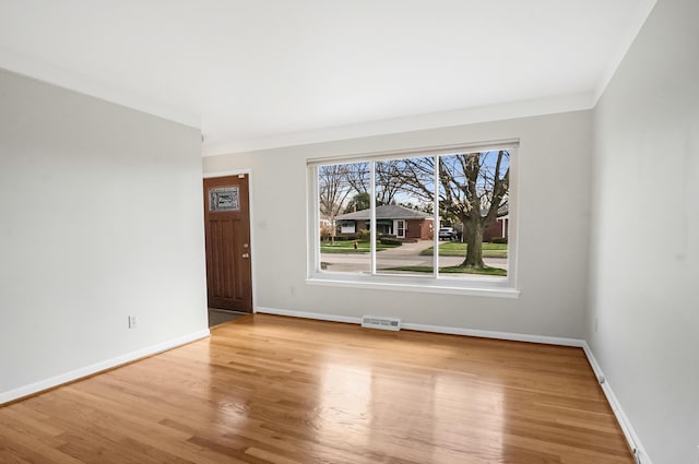 empty room featuring visible vents, baseboards, crown molding, and wood finished floors