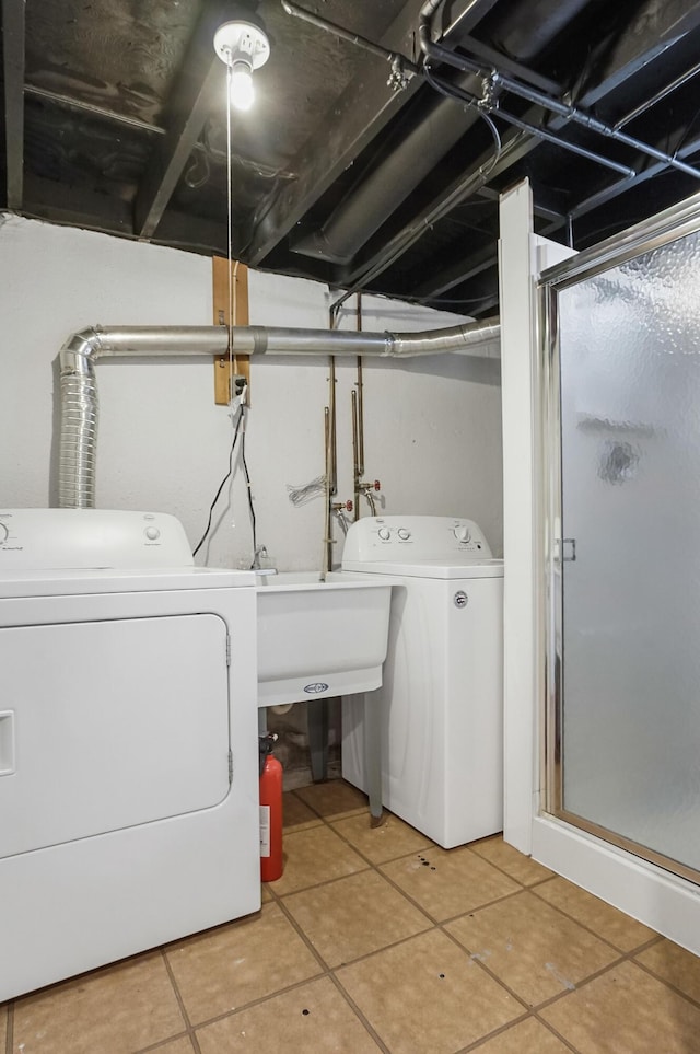 laundry area with laundry area, washer and clothes dryer, a sink, and light tile patterned floors