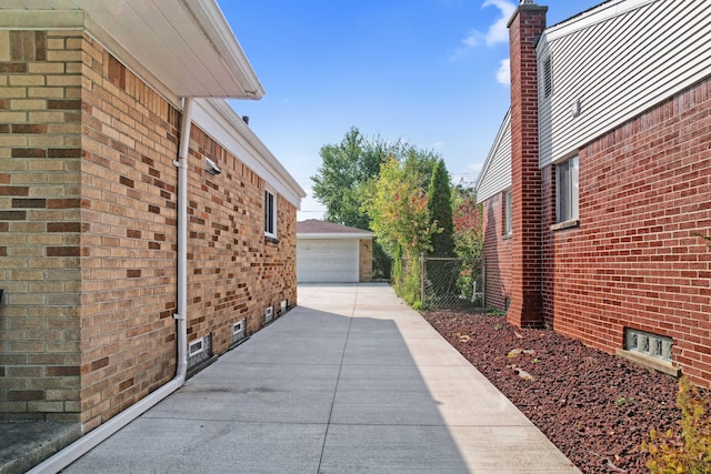 view of side of property featuring a garage, fence, an outbuilding, and brick siding