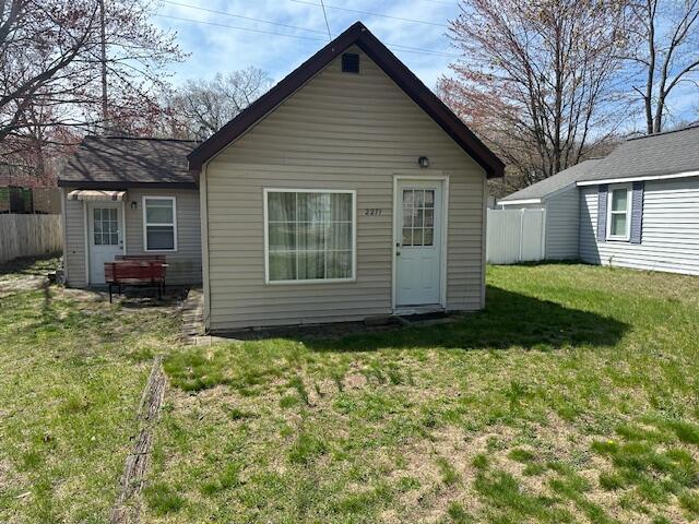 rear view of property featuring a yard and fence
