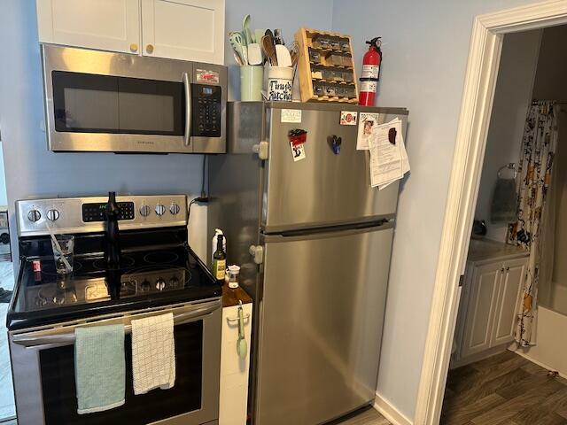 kitchen featuring appliances with stainless steel finishes, white cabinets, and wood finished floors