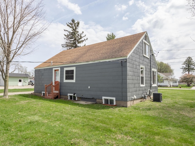 rear view of house with a shingled roof, central AC, a yard, and entry steps