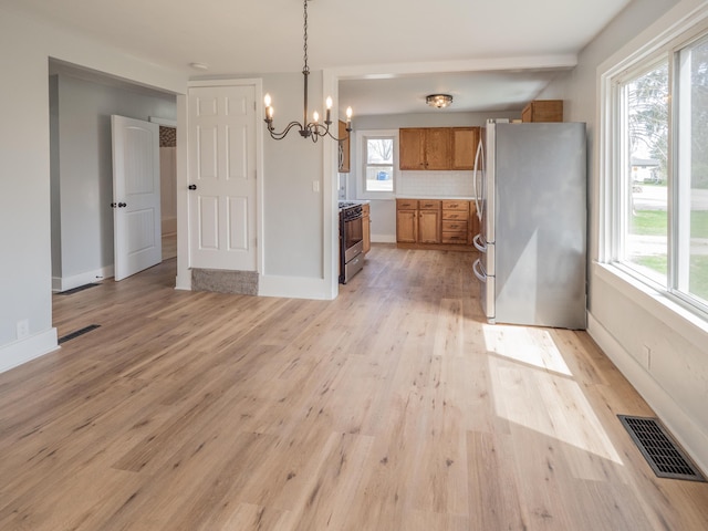 unfurnished dining area with visible vents, a wealth of natural light, an inviting chandelier, and light wood-type flooring