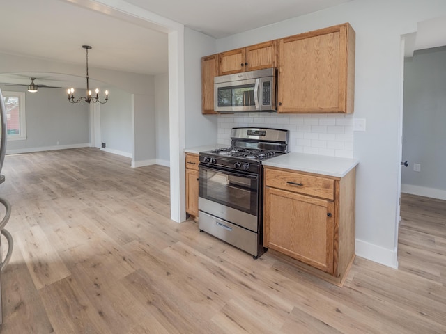kitchen featuring baseboards, light countertops, light wood-style flooring, appliances with stainless steel finishes, and backsplash