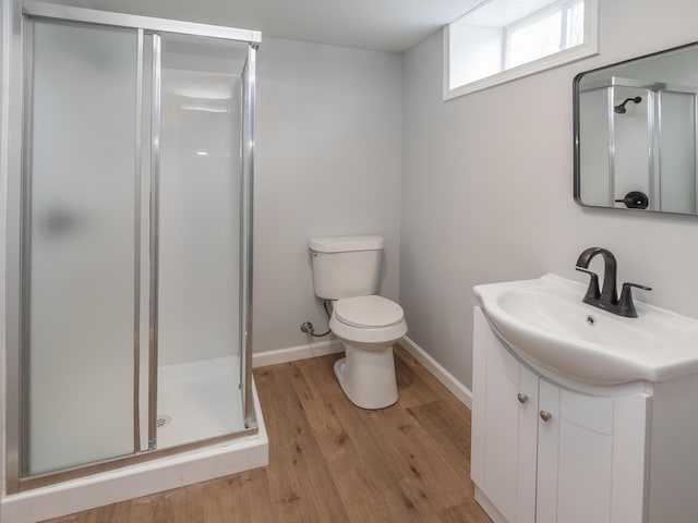 full bathroom featuring vanity, toilet, baseboards, wood finished floors, and a stall shower