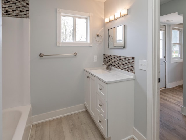 full bathroom featuring vanity, baseboards, wood finished floors, and tasteful backsplash