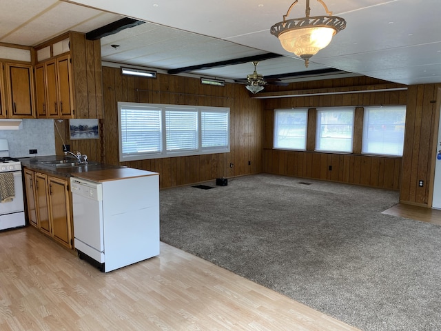 kitchen with brown cabinetry, white appliances, open floor plan, ceiling fan, and wooden walls