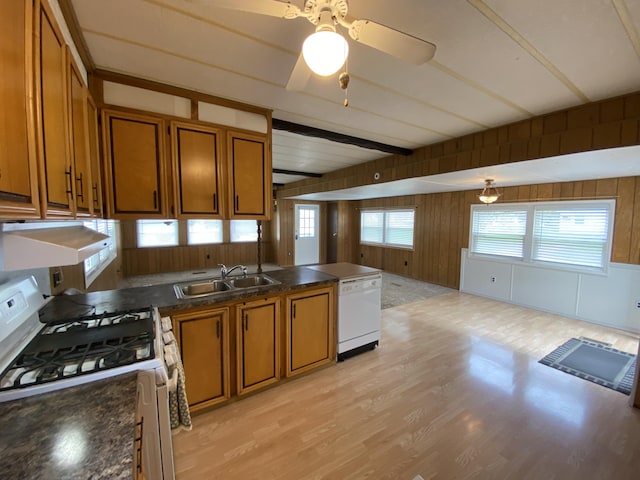 kitchen with dark countertops, white appliances, light wood-type flooring, brown cabinets, and a sink