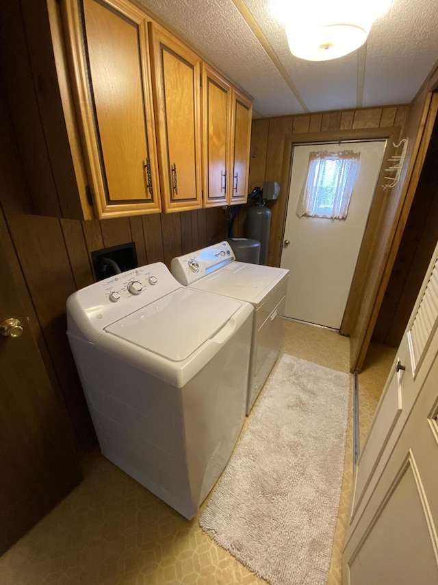 laundry room featuring cabinet space, wood walls, and washing machine and clothes dryer