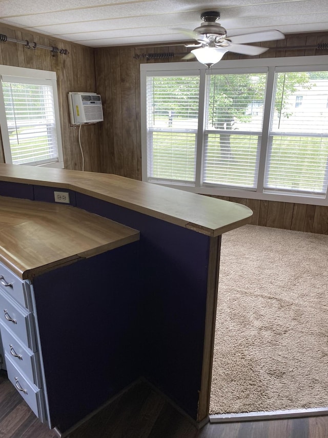 kitchen with wooden walls, a ceiling fan, wooden counters, and plenty of natural light