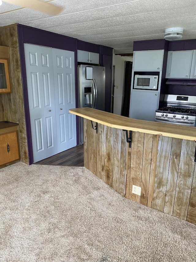 kitchen featuring appliances with stainless steel finishes, wooden counters, and a breakfast bar