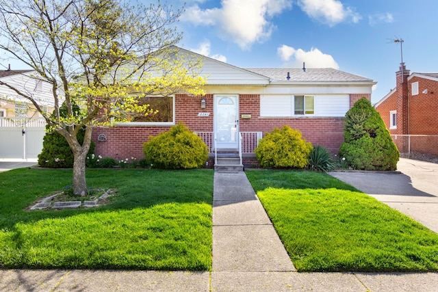 bungalow featuring fence, a gate, a front lawn, and brick siding
