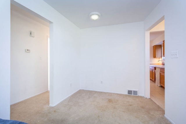 interior space with light colored carpet, baseboards, visible vents, and a sink