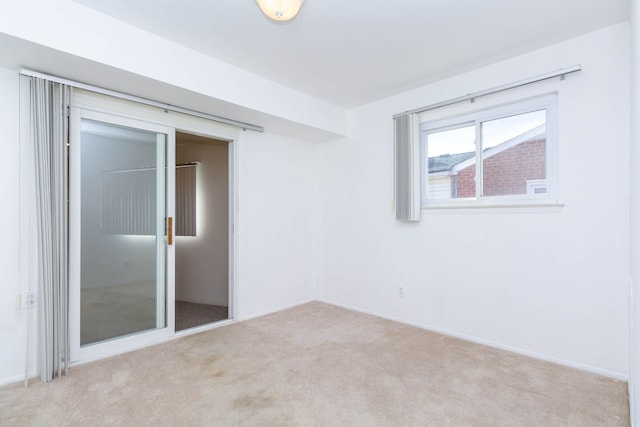 unfurnished room featuring baseboards and light carpet