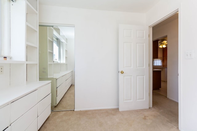 walk in closet with a ceiling fan and light colored carpet