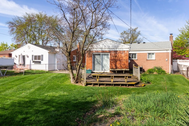 back of property with brick siding, a wooden deck, a fenced backyard, a chimney, and a yard