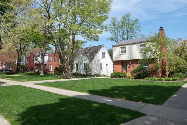 view of front of home featuring brick siding, a front lawn, and a chimney
