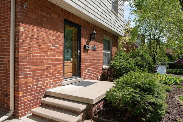 doorway to property featuring brick siding and mansard roof