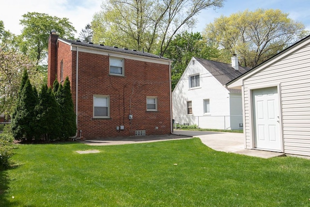 back of house featuring a chimney, a yard, brick siding, and a patio area
