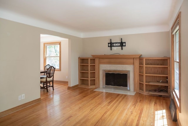 living room with wood finished floors, a fireplace with flush hearth, and baseboards