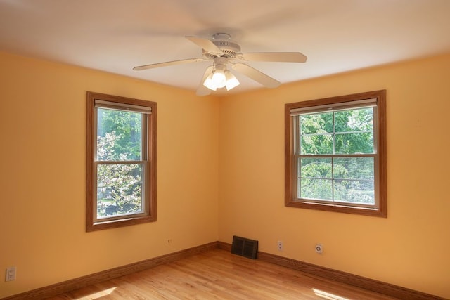 spare room featuring healthy amount of natural light, light wood-type flooring, baseboards, and ceiling fan